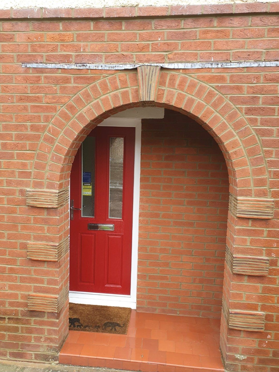 Brick arch porch with a red front door