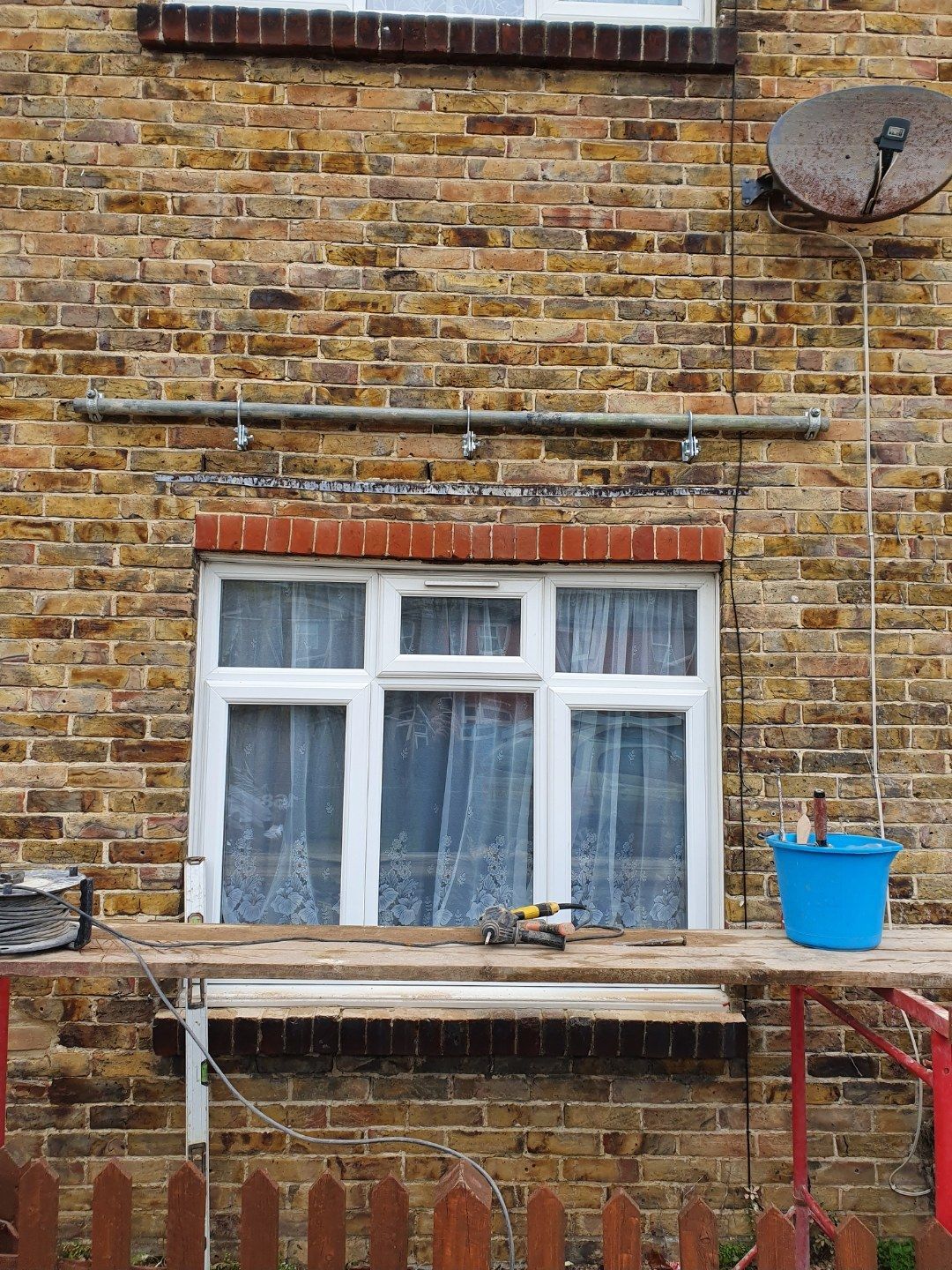 Yellow stock brick wall partway through repointing